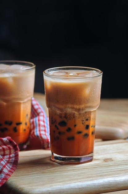 Ein Glas Eistee mit Bubble Tea auf einem Holztisch.