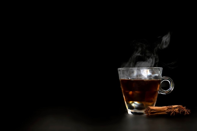 Ein Glas frisch gebrühter schwarzer Tee, der dampfwarmen, weichen, dunkleren Hintergrund kopiert