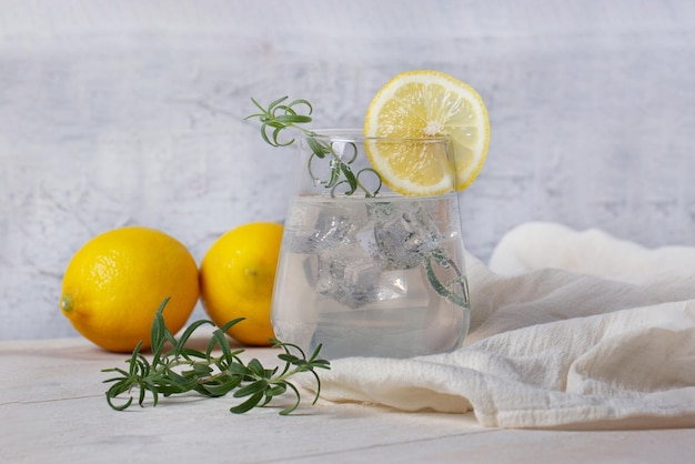 Ein Glas frische Limonade mit Eis, Rosmarinzweigen und Zitronen