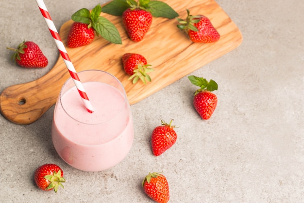 Ein Glas frischen Erdbeermilchshake auf rosa Hintergrund