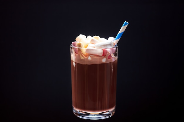 Ein Glas heiße Schokolade mit bunten Marshmallows und einem Trinkhalm