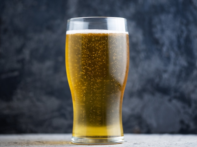 Ein Glas helles Bier auf einem dunklen Hintergrund