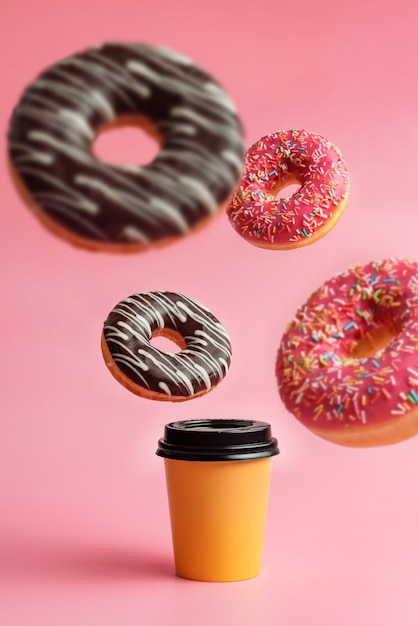 Ein Glas Kaffee und schwebende Donuts auf rosafarbenem Hintergrund