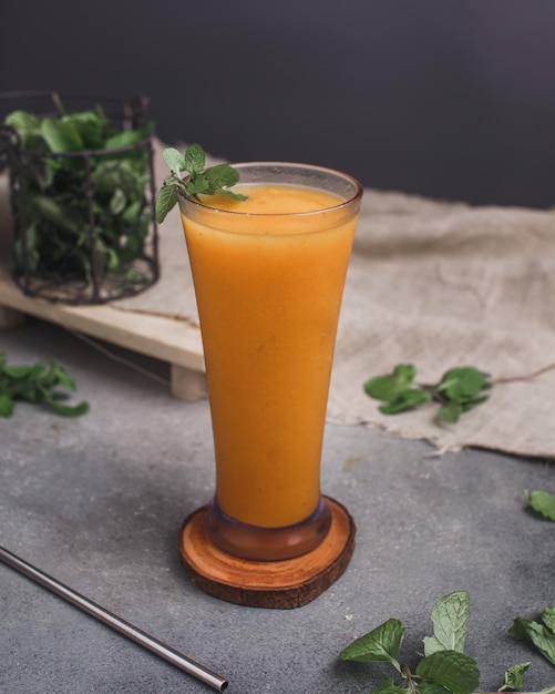 Foto ein glas karotten-smoothie auf einem holzuntersetzer