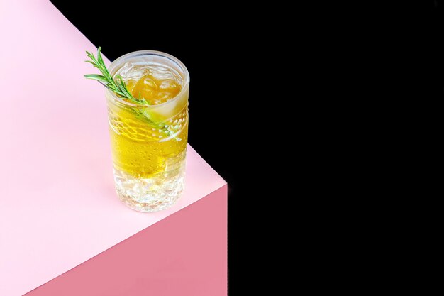 Ein Glas Kombucha-Cocktail mit Eis und einem Zweig Rosmarin