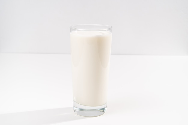 Ein Glas Milch auf weißem Hintergrund. Verkauf von landwirtschaftlichen Produkten. Platz für die Inschrift.