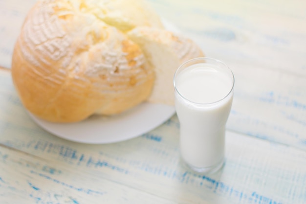 Ein Glas Milch und Weißbrot auf einem hölzernen Hintergrund