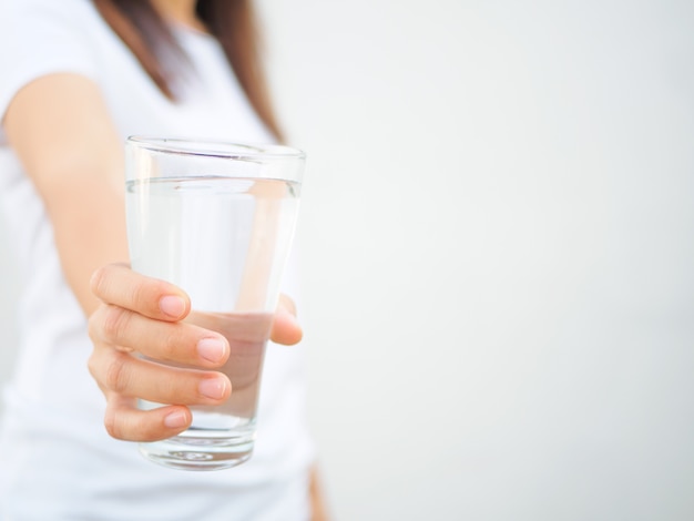 Ein Glas Mineralwasser in den Händen der Frau. Konzept des gesunden Getränkes.