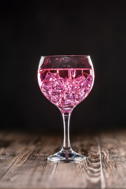 Foto ein glas mit einem rosa cocktail gefüllt mit eis auf dunkler oberfläche