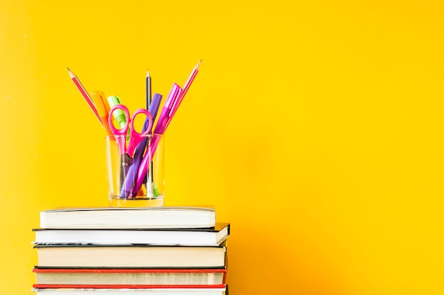 Ein Glas mit Stiften, Bleistiften und Schere auf einem Stapel Bücher für die Ausbildung