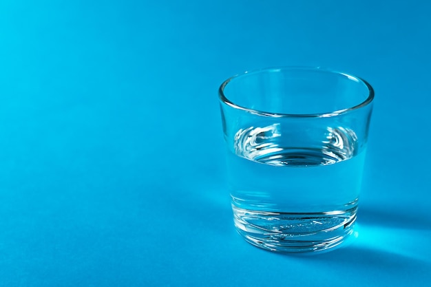 Ein Glas mit Wasser in einem blauen Farbhintergrund