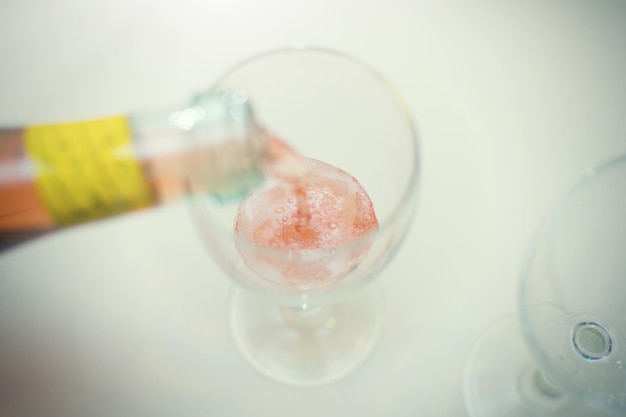 Ein Glas rosa Champagner einschenken