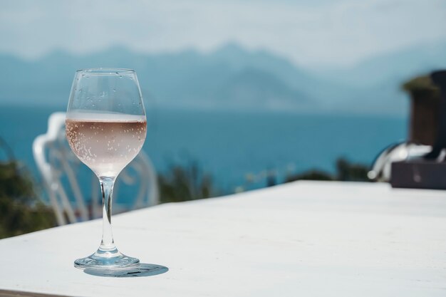 Ein Glas Roséwein auf dem Tisch eines Straßencafés vor dem Hintergrund des Mittelmeers und...