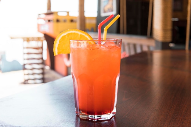 Ein Glas roter Saft auf einem Holztisch Nahaufnahme Oktail aus süßem Bourbon-Whiskey-Getränk, garniert mit Orangenschale auf Tisch-Diner-Stand mit verschwommenem Bokeh-Restaurant-Hintergrund