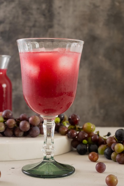 Ein Glas Rotwein mit Trauben auf einem Tisch.