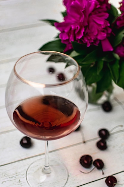 Foto ein glas rotwein neben blumen in einer vase auf hellem hintergrund, alkoholfreier wein