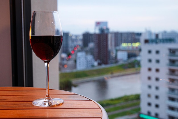 Ein Glas Rotwein steht auf einem Tisch vor einem Fenster mit Blick auf die Stadt.