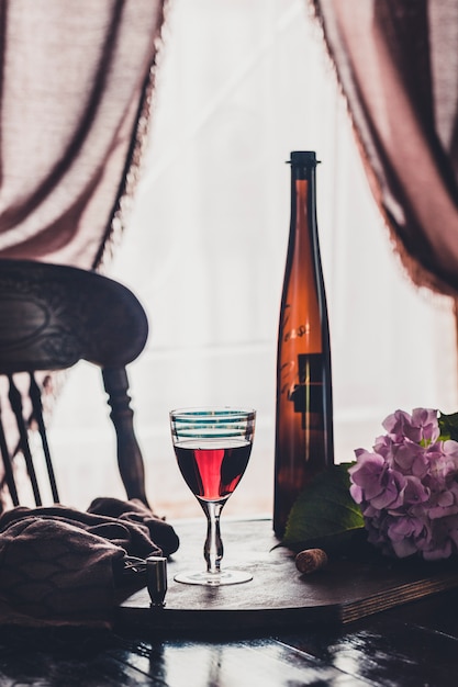 Ein Glas Rotwein und eine Flasche auf dunklem Holz