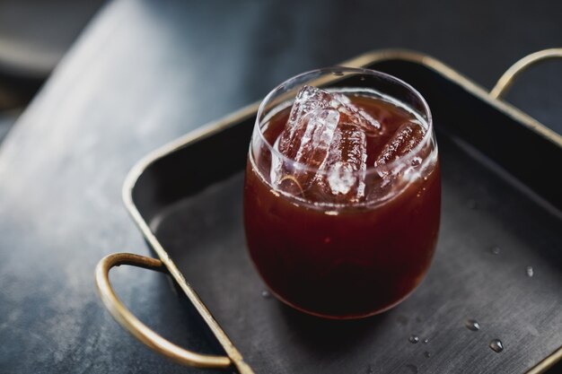 Ein Glas schwarzer Eiskaffee in einem Metalltablett auf dem Tisch im Loft-Café?