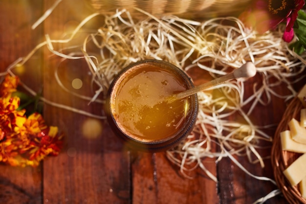 Ein Glas süßer Honig in einem Eimer auf einem Holztisch im Garten mit Blumen zum Frühstück leckeres Essen