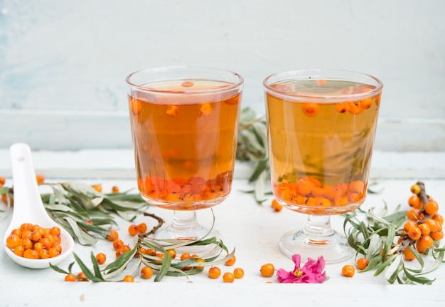 Ein Glas Tee mit Sanddornbeeren auf einem rustikalen hölzernen Hintergrund