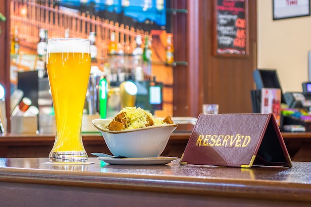 Ein Glas ungefiltertes Bier mit Zwiebackkäse, eine Tablette - steht auf einem Holztisch in der Restaurantbar.