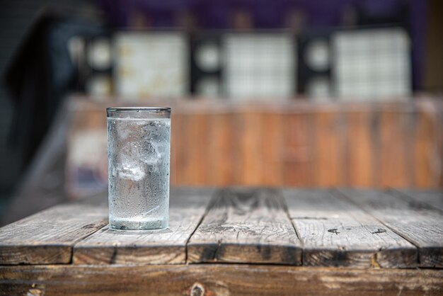 Ein Glas Wasser, das auf einem alten Holztisch platziert ist, konzentriert sich nur auf einige Punkte des Bildes