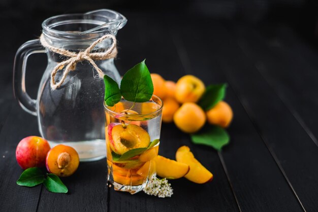 Ein Glas Wasser mit Pflaumen- und Aprikosenstücken im Inneren. Platz kopieren. Gesundes Essen, Entgiftung