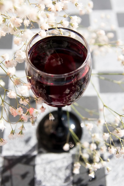 Foto ein glas wein auf einem schachbrett frühlingsstimmung white gypsophila auf schwarzem hintergrund