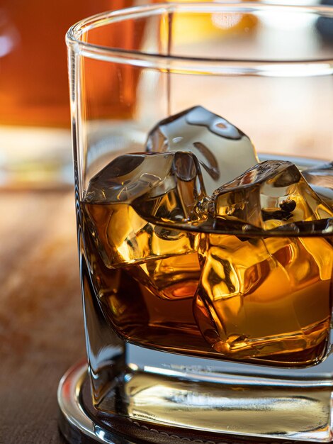 Foto ein glas whiskey auf eis auf einer holztheke mit flaschen im hintergrund
