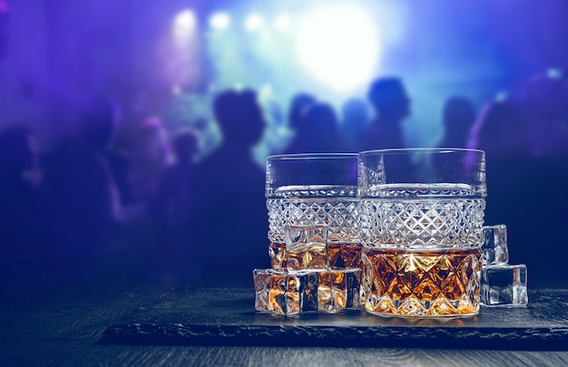 Ein Glas Whisky auf einer Theke in einer Bar in einem Nachtclub vor dem Hintergrund der Besucher