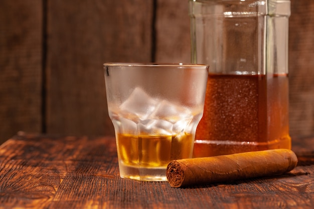 Ein Glas Whisky und Zigarre auf Holztisch