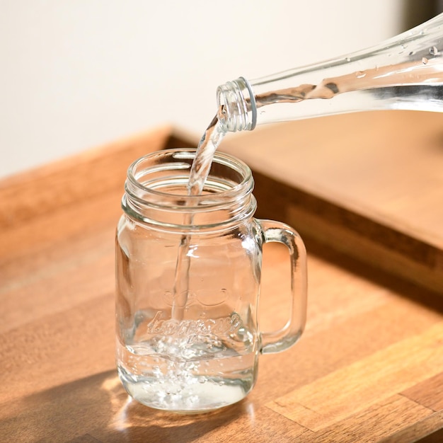 Ein Glasgefäß, in das eine Flasche Wasser gegossen wird.