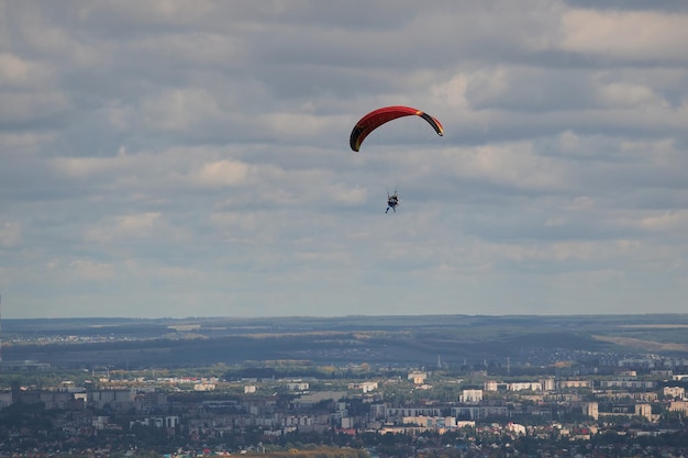 Ein Gleitschirm fliegt am blauen Himmel vor dem Hintergrund von Wolken. Gleitschirmfliegen am Himmel an einem sonnigen Tag