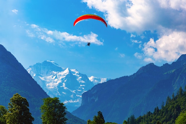 Ein Gleitschirm über Interlaken, wichtiges Touristenzentrum im Berner Oberland, Schweiz. Die Jungfrau ist im Hintergrund sichtbar