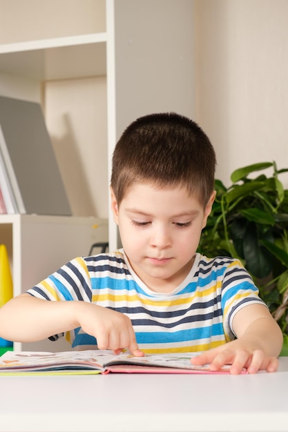 Ein glücklicher 4-jähriger Junge schaut sich ein Buch mit Bildern an