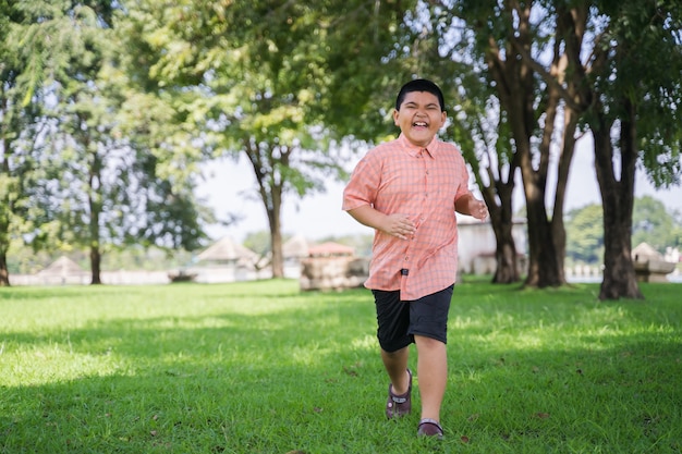 Ein glücklicher asiatischer Junge, der in den Park im Freien in den Feiertagen läuft