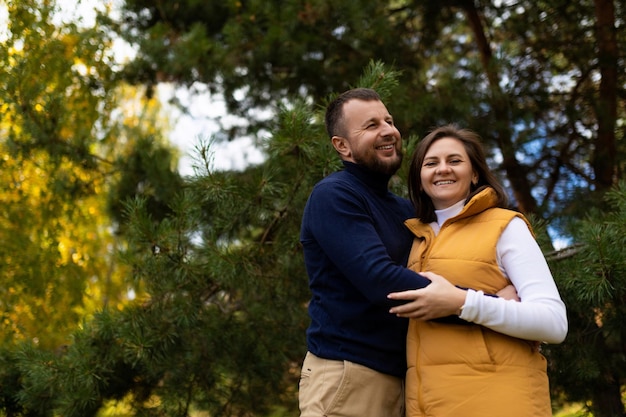 Ein glücklicher Ehemann umarmt seine Frau freudig vor dem Hintergrund eines Herbstwaldes