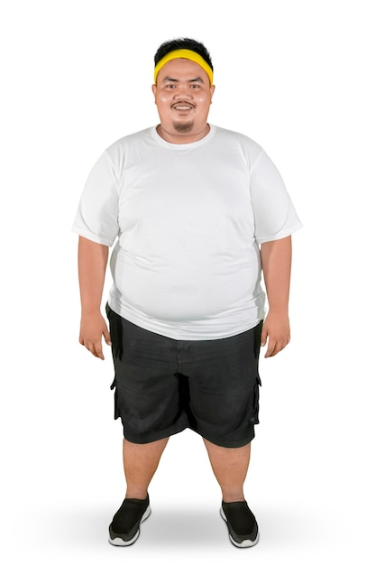 Ein glücklicher fetter Mann steht mit Sportkleidung im Studio