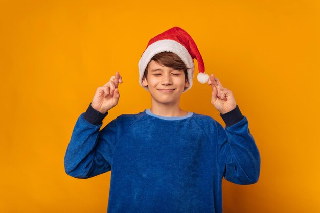 Ein glücklicher Junge, der die Finger kreuzt und sich das beste Weihnachtsgeschenk wünscht.