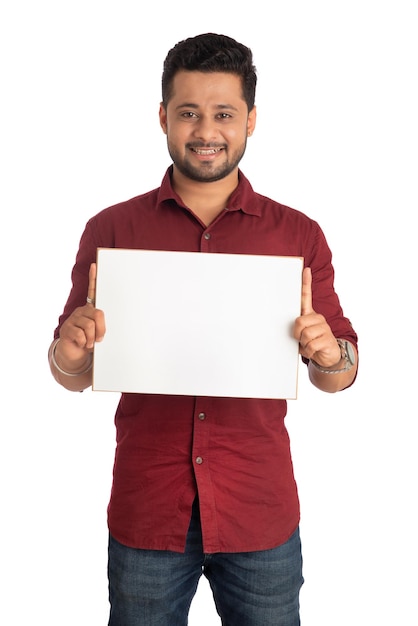 Ein glücklicher junger Mann, der ein Schild oder Plakat in seinen Händen auf einem weißen Hintergrund hält und anzeigt