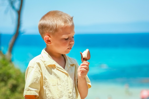 Ein glücklicher Kinderjunge mit Eis am Meer in der Natur in der Parkreise