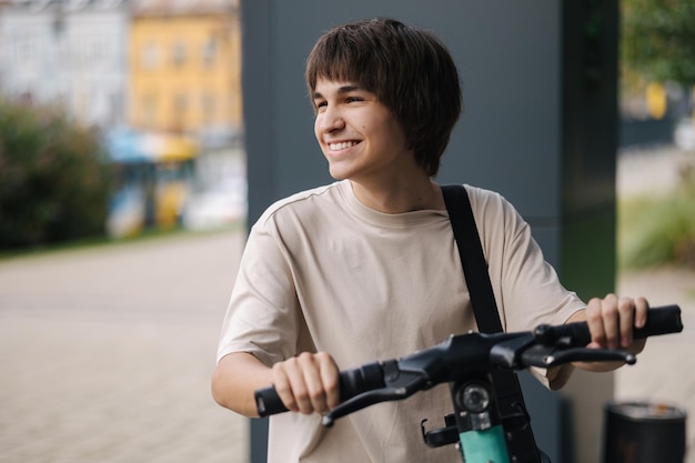 Ein glücklicher lächelnder Teenager, der einen elektrischen Roller benutzt, eilt aufs College.