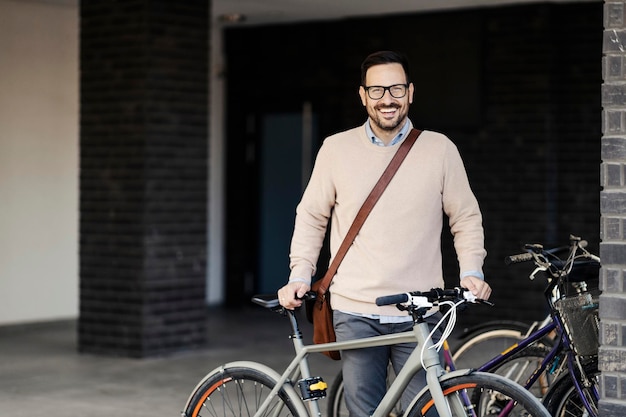 Ein glücklicher Mann, der auf einem öffentlichen Platz steht und mit dem Fahrrad posiert