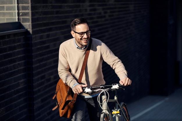 Ein glücklicher Mann, der ein Fahrrad auf der Straße bergauf schiebt