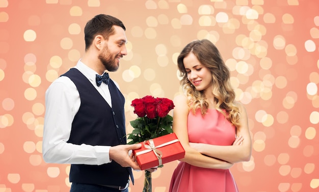 ein glücklicher Mann, der einer Frau Blumen und Geschenke schenkt