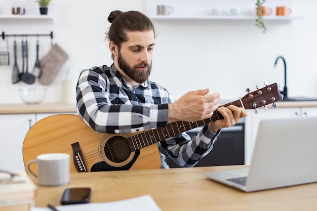 Ein glücklicher Mann unterrichtet Online-Gitarrenunterricht mit modernen Technologien