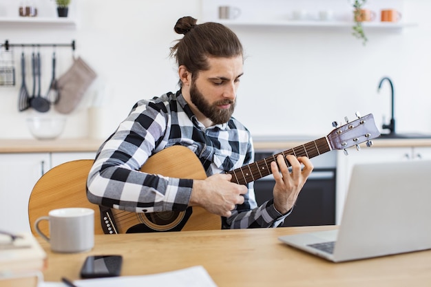 Ein glücklicher Mann unterrichtet Online-Gitarrenunterricht mit modernen Technologien