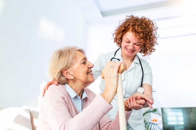 Ein glücklicher patient hält die pflegekraft für eine hand, während er zeit miteinander verbringt. ältere frau im pflegeheim und krankenschwester.