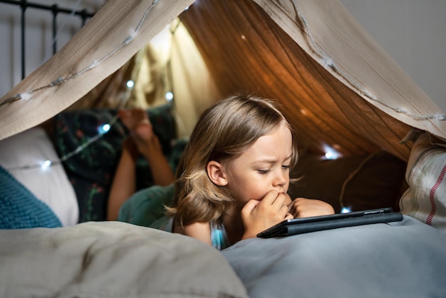 Foto ein glücklicher, süßer kleiner junge spielt zu hause in einem teepee-zelt